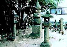竹林の横に中央に高さ2メートルあまりの五輪塔、五輪塔南側に一対の石灯篭が建てられている写真