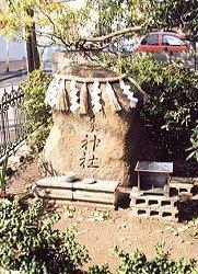 大きな岩にしめ縄が飾られ、飲み物などのお供え物があり、池田の野神さまが祀られている写真