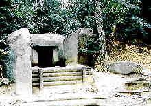 巨石をくり抜き入口部分が開いている石宝殿(いしのほうでん)古墳の写真
