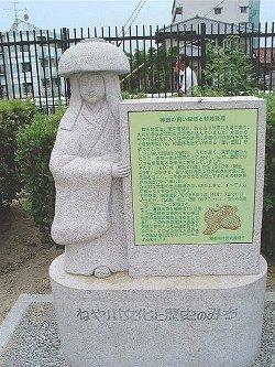 鉢かつぎ姫の形をした石像が説明看板を持っている写真