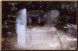 巨石をくり抜き入口部分が開いている石宝殿(いしのほうでん)古墳の写真