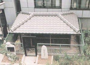 入口に石碑があり、柵で囲いがしてある屋根付きの弘法井戸の写真