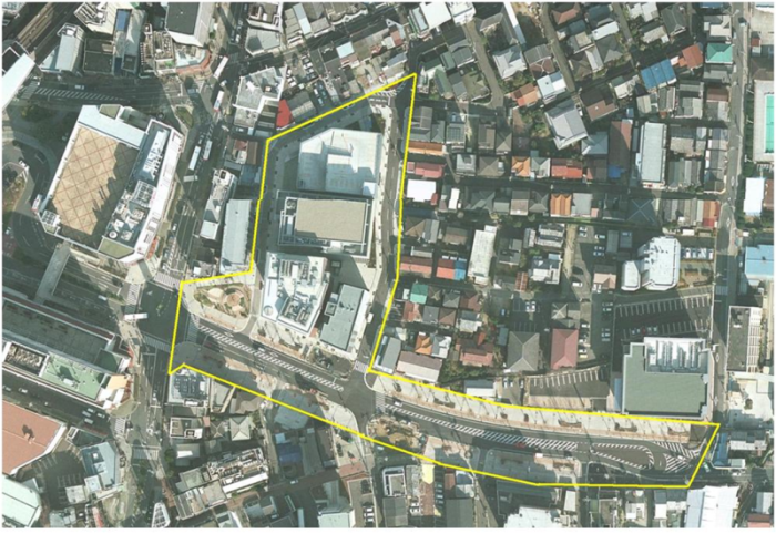 一部が黄色い線で囲んである建物と道路を上空から写した写真