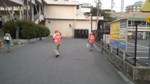 香里園駅前で1名のオレンジ色のベストを着た人が啓発活動を行っている写真