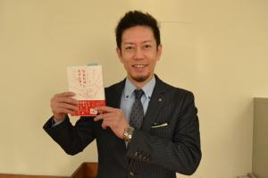 「なみだのラブレター」の本を持って笑顔で写っている橋本昌人さんの写真