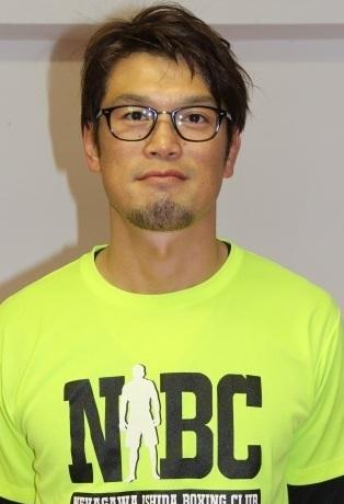 黄色いシャツを着て眼鏡をかけている石田さんの写真