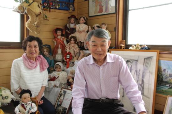 沢山のアンティーク人形や絵画が並んでおり、滋野さん夫妻が笑顔で写っている写真
