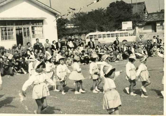 成田山不動尊の山門前にある成田幼稚園の運動会で両親たちが見守るなか園児たちが行進している白黒写真