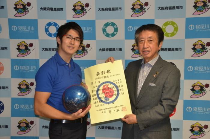 右手にボーリングのボールを持っている浦口健一さんが市長と一緒に表彰状を持って写っている写真
