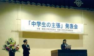 「中学生の主張」発表会と書かれた横断幕の演台前で発表をしており、左側の男性が手話通訳をしている写真