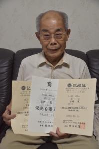 賞状と記録証を持って笑顔で写っている吉岡さんの写真