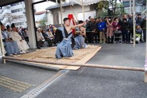 友呂岐神社で若者2人が紋付・かみしも姿で弓を引いており、その様子を見に訪れた見物客の写真