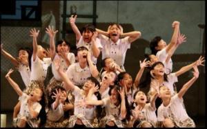 舞台上に集まって手を伸ばしたり、口元を押さえたりして熱演している子供たちの写真