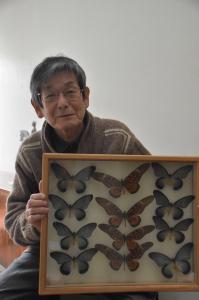 蝶の標本を持った田根徹さんの写真