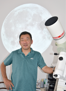 天体望遠鏡の横で腰に手をあてて立っている向井弘さんの写真