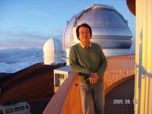 望遠鏡があるマウナケア山頂の観測施設前で記念撮影している仲野誠さんの写真