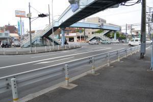 信号機のある道路を車が走行しており、歩道橋が設置されている写真