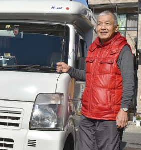 愛車のキャンピングカーの横に立っている松野 一弘さんの写真