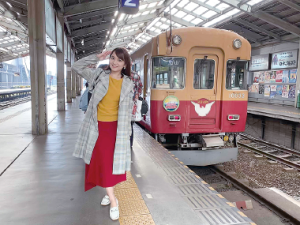 線路に電車が停まっておりプラットホームで敬礼をしている久野知美さんの写真