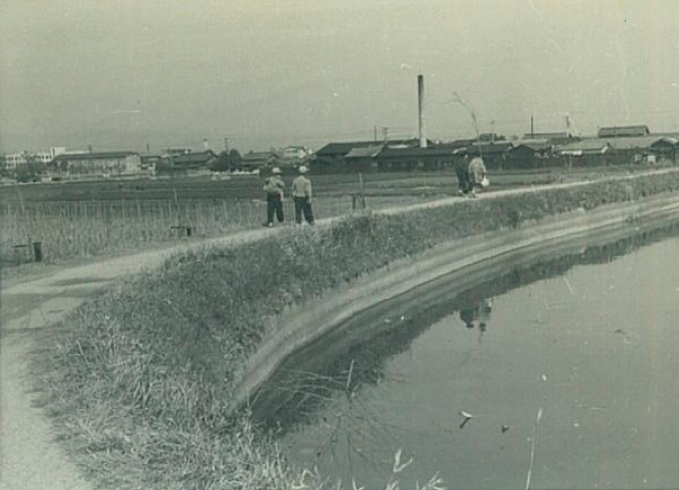 田んぼと池の間のあぜ道を学生2人が歩いている五藤池昭和36年の白黒写真