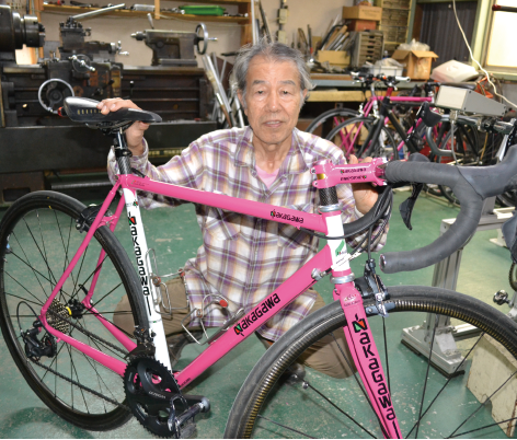 ピンク色に塗装されたロードレース用の自転車と中川さん