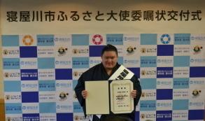 寝屋川市ふるさと大使委任状を手に記念撮影している豪栄道豪太郎関の写真