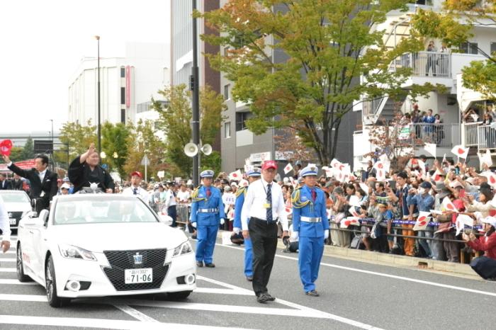 豪栄道関の優勝を祝してパレードが行われています。車には豪栄道関と市長が乗り沿道の方々に手を振っている様子を左前方から写した写真