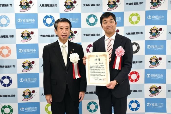 表彰状を持っている門井さんと寝屋川市長の写真