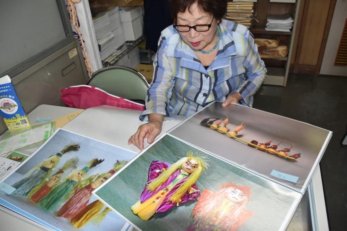 野菜で作った作品の資料を見ている小森敏枝（蓮）さんの写真