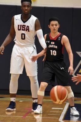 白いユニフォームを着た長身選手の前に立ちバスケットボールの方を見ている黒色ユニフォームを着た森井さんの写真