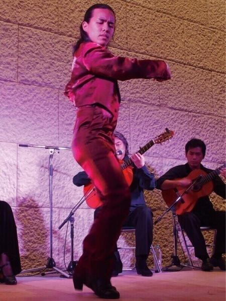 フラメンコを踊っている出水さんと後方でギターを弾いている2名の男性の写真