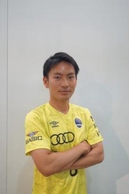 黄色いシャツを着て腕を組んでいる松岡さんの写真