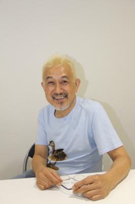 鳥が描かれたTシャツを着て笑顔で写っている中川五郎さんの写真