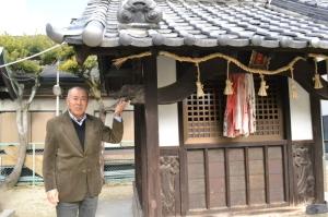 中川恒民さんが若宮神社の象の細工を左手で指さしている写真