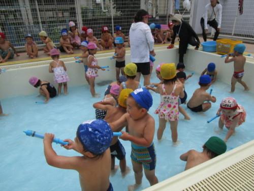 プールの中で水鉄砲で遊ぶ子供たちの写真