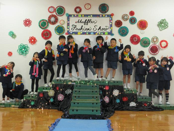 きれいにデコレーションされた舞台の上でマフラーをした子供たちがポーズをとっている写真