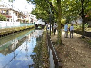 友呂岐水路と横の歩道はフェンスで区切られており、歩道沿いには木が植えられている写真