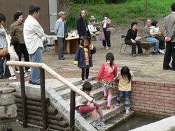親が見守る中、4名の女児が小川に通じる階段で遊んでいる写真