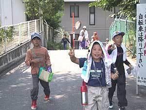 3人の子供たちがピースサインをして歩いている写真