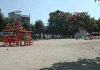 広い公園敷地の一角に赤色や黄色などカラフルな色で作られた遊具が設置してある写真
