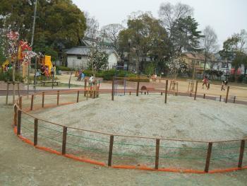 円形状に土が盛られている周りに柵がしてあるみどりの広場の写真