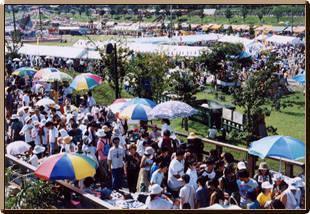 テントやパラソルが建てられた打上川治水緑地のイベント会場がたくさんの人で賑わっている写真
