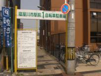 「寝屋川市駅前第1自転車駐車場」の看板が建てられた駐車場入口の写真