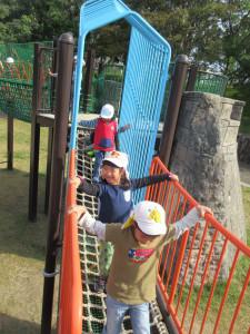足元が網になっている遊具を3人の子供たちが順番に歩いている写真