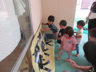 壁に立てかけられたばいきんまんの絵を子供たちが見たり触っている写真