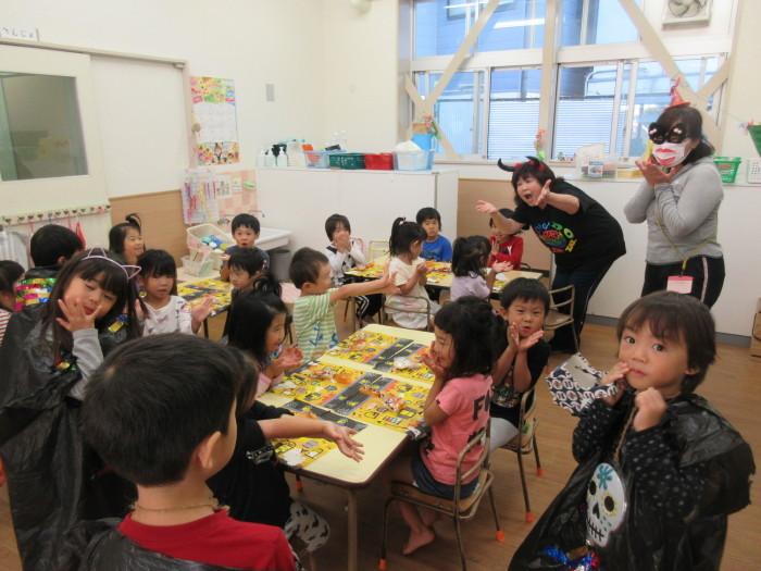 机に子供たちが座っていて、周りにお化けの恰好をした子供3人と保育士2人が立っている写真