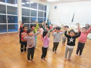 12人ほどの幼児が立っていて、両手を上にあげて踊ろうとしている写真