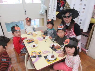 頭にパンプキンの飾りをつけた子供5人と、とんがり帽子をかぶった保育士が写っている写真
