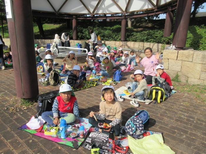 シートの上に座っている子供たちがお弁当を食べている写真