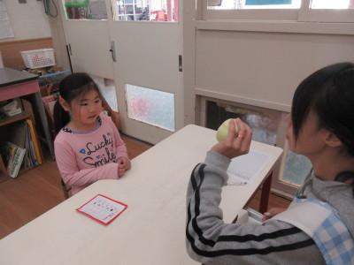 ボールのような丸いものを女性が握っていて、前に座っている女の子に見せている写真